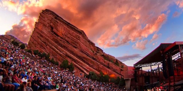 A Group Of People Standing In Front Of Red Rocks Amphitheatre
