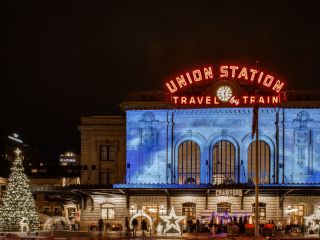 A Sign Above A Store Front At Night With Union Station In The Background